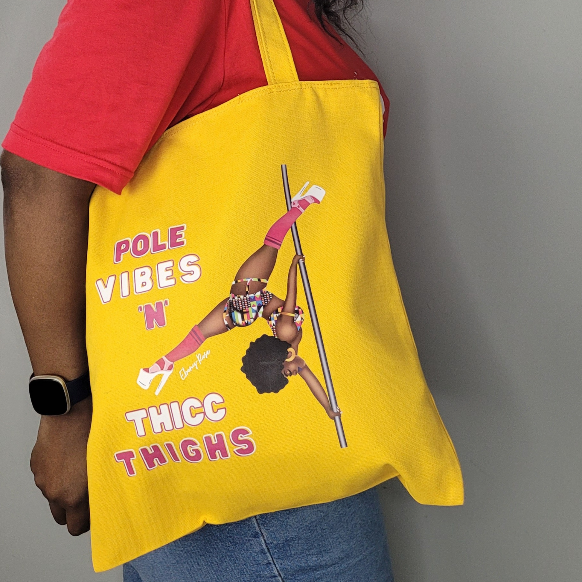 yellow tote bag featuring a black pole dancer wearing bright African inspired Afrocentric garter pole shorts and sports top Bright pink knee socks and clear platform heels in an extended butterfly pose with slogan affirmation pole vibes n thicc vibes