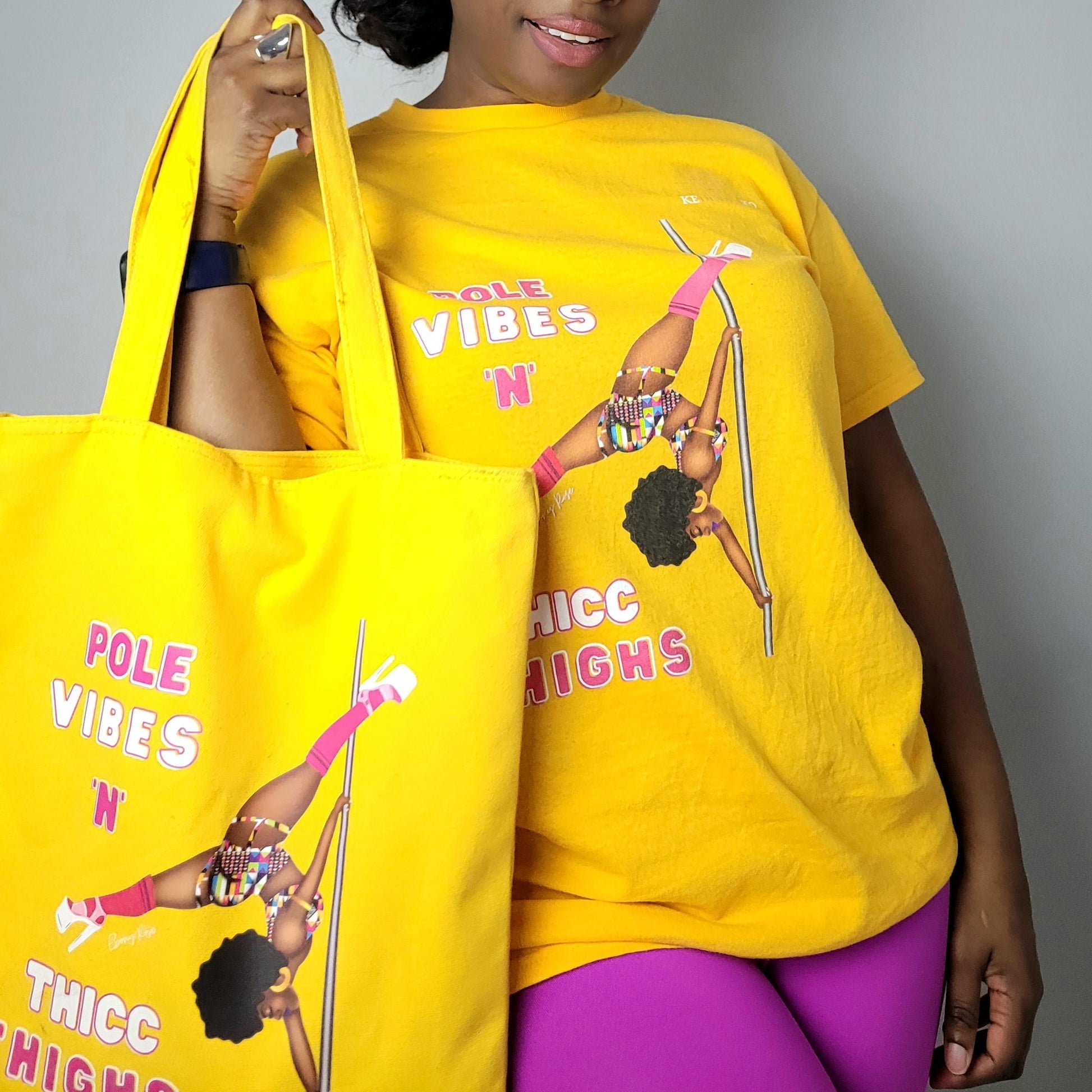Yellow unisex t-shirt  featuring a black pole dancer wearing bright African inspired Afrocentric garter pole shorts and sports top. Bright pink knee socks and clear platform heels in an extended butterfly pole pose with slogan affirmation pole vibes n thicc vibes
