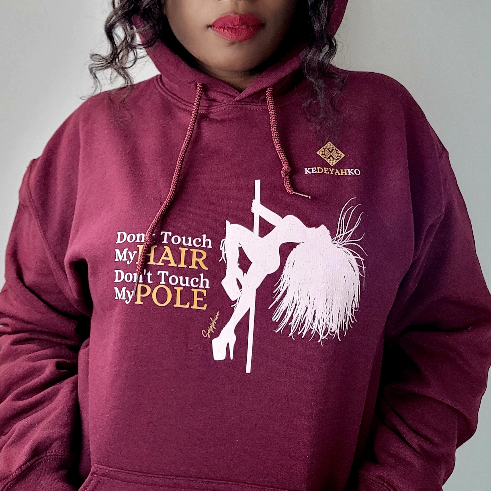 Maroon hoodie showing a white silhouette of a pole dancer with long braids wearing platform heels with the slogan don’t touch my hair don’t touch my pole