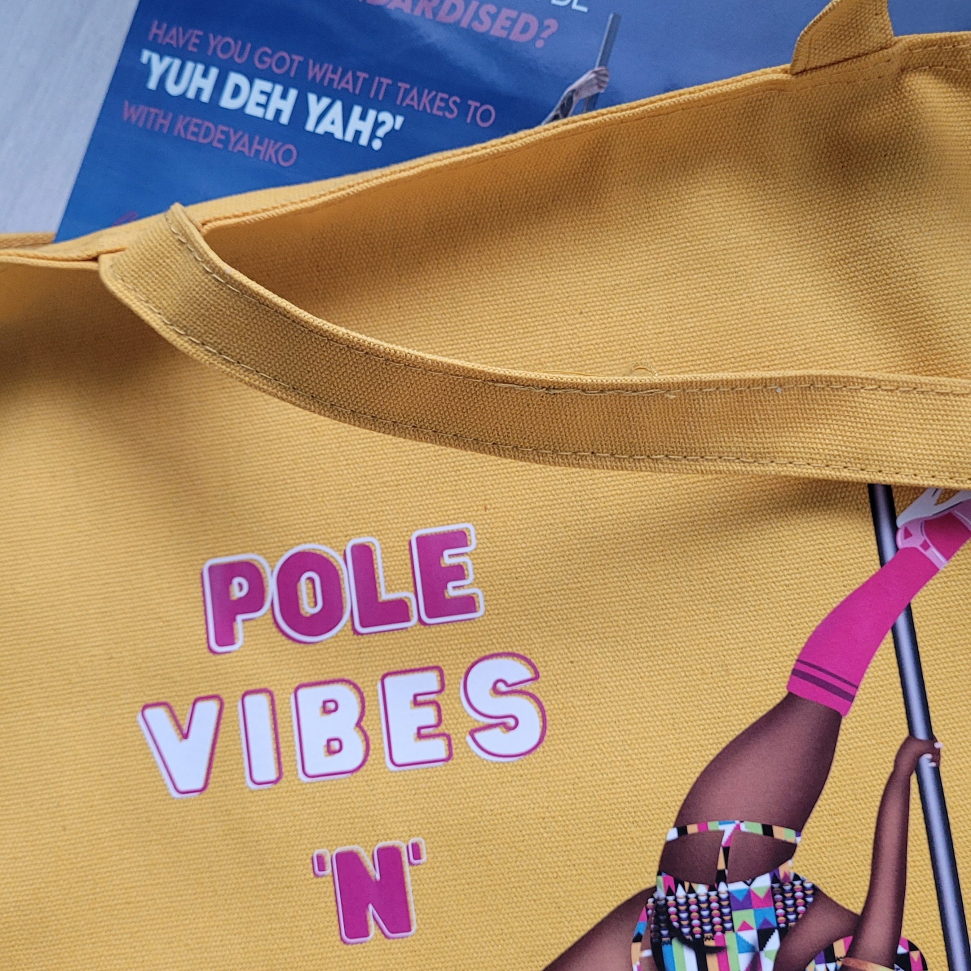 yellow tote bag featuring a black pole dancer wearing bright African inspired Afrocentric garter pole shorts and sports top Bright pink knee socks and clear platform heels in an extended butterfly pose with slogan affirmation pole vibes n thicc vibes