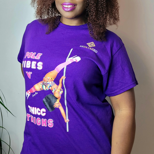 Purple unisex t-shirt  featuring a black pole dancer wearing bright African inspired Afrocentric garter pole shorts and sports top. Bright pink knee socks and clear platform heels in an extended butterfly pole pose with slogan affirmation pole vibes n thicc vibes
