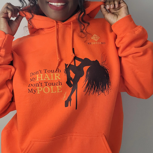 Orange hoodie showing a black silhouette of a pole dancer with long braids wearing platform heels with the slogan don’t touch my hair don’t touch my pole 
